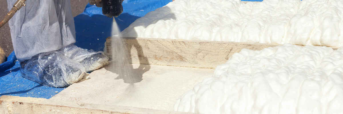 Technician spraying foam insulation using plural component spray gun. spraying polyurethane foam for roof